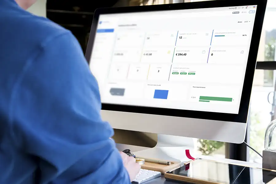Operatore alla scrivania su iMac con la dashboard Bonus Tariflow: statistiche e pratiche visibili